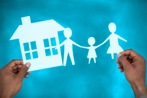 Man holding paper cut out family and house on blue background